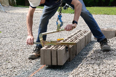 Person using a tool to work on concrete blocks outdoors