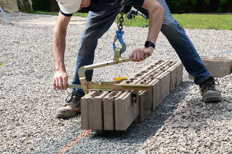 Person using a tool to work on concrete blocks outdoors