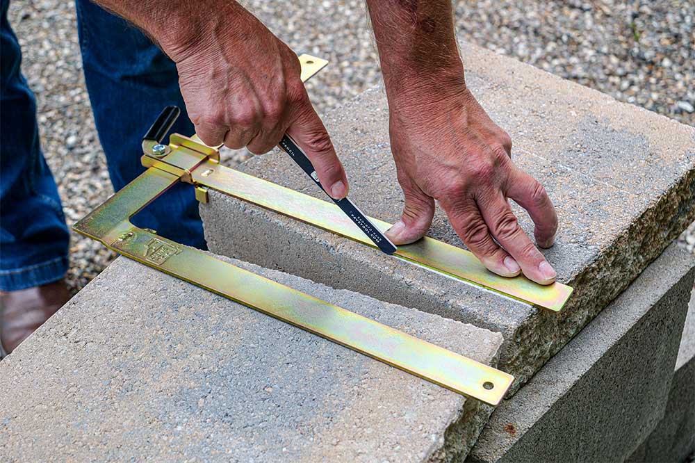 A person using a Quick-E-Parallel Marking Gauge to draw a line on a concrete block.